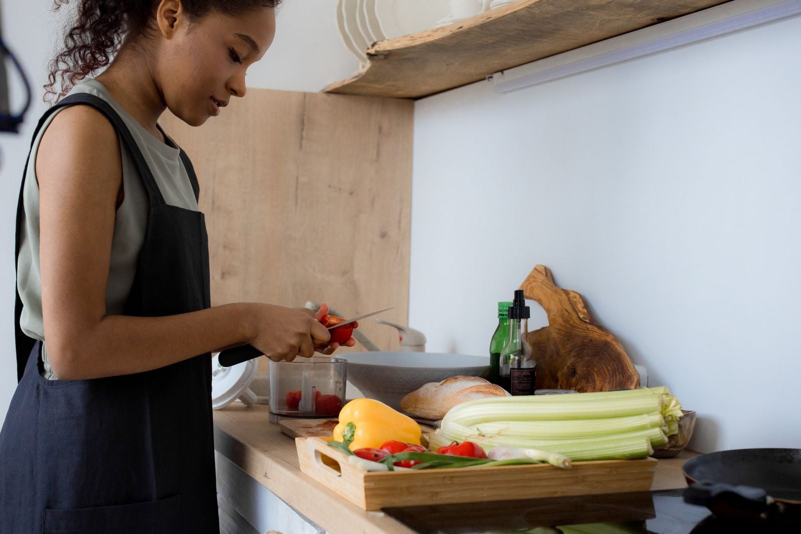 Woman slicing fresh vegetables beside peppers and celery on a kitchen counter