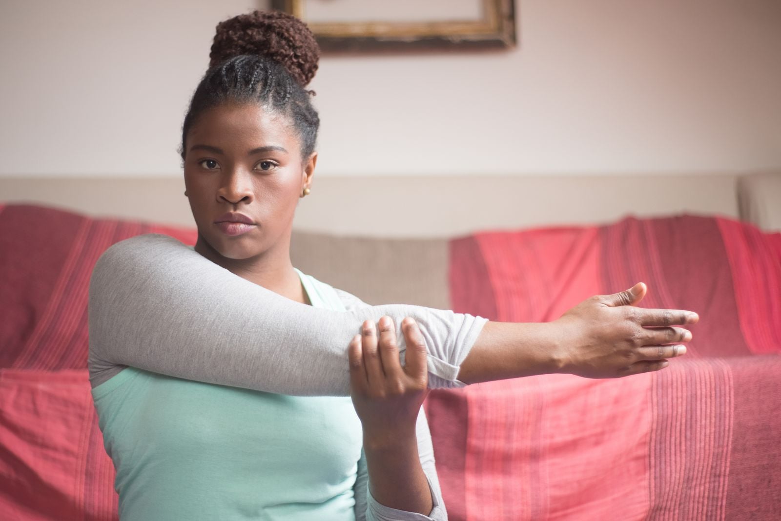 Woman stretching her straightened arm across her body at home