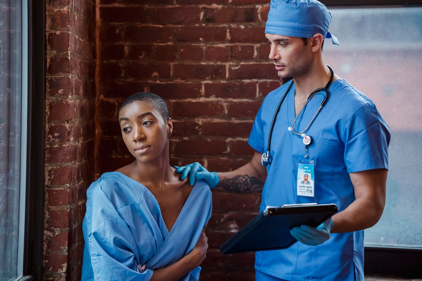 Clinician checking a seated woman's shoulder while reviewing notes on a clipboard