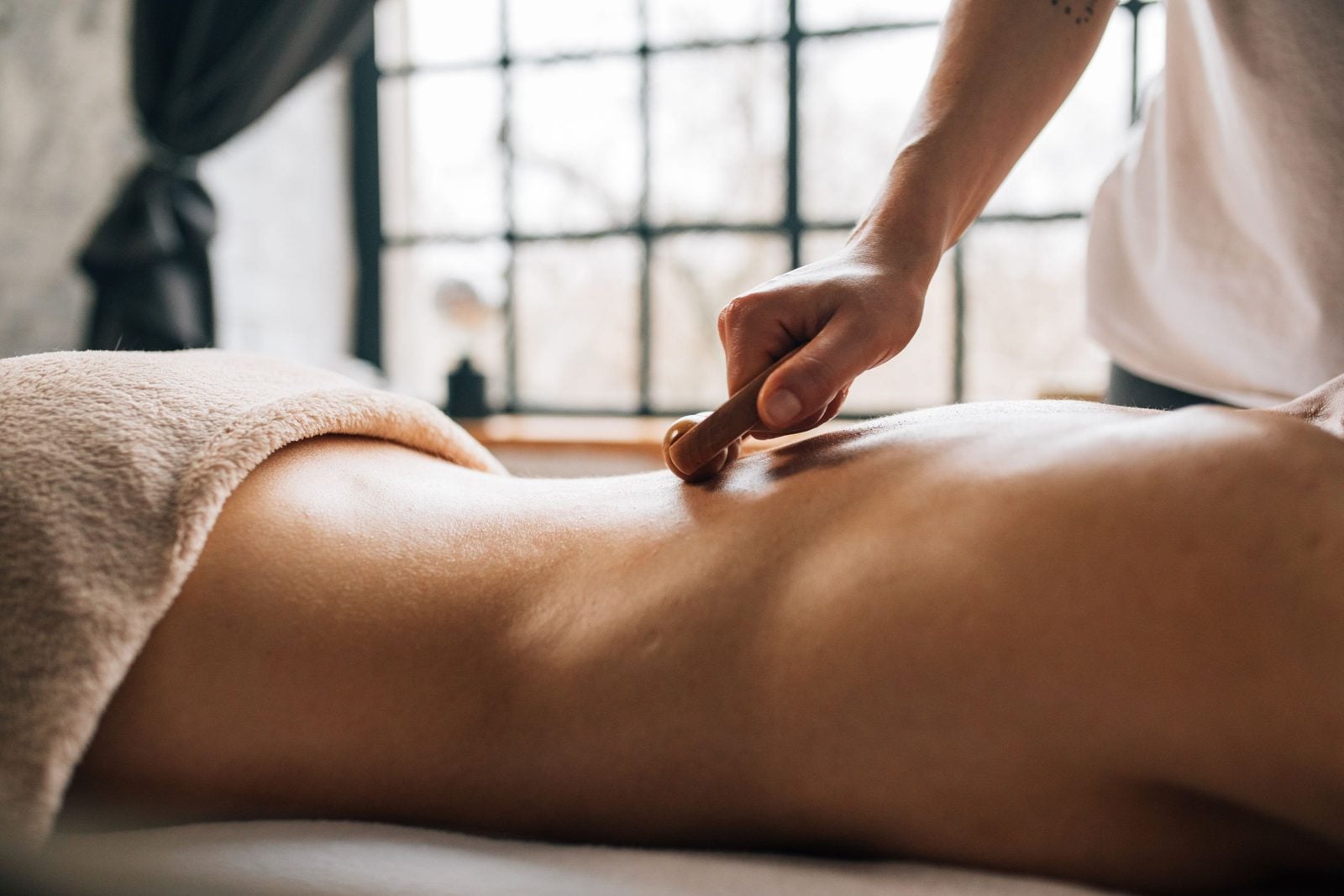 Illustrative stock photo of a handheld tool being used along the muscles of the lower back