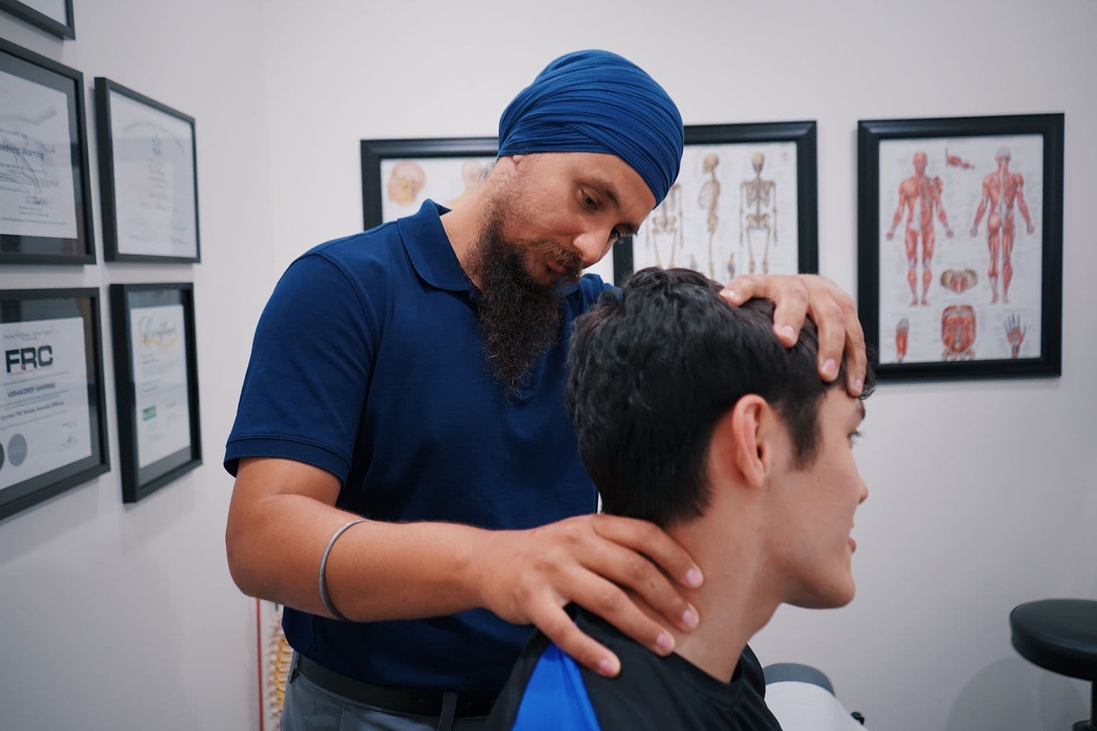 Clinician checking a young man's neck in a treatment room