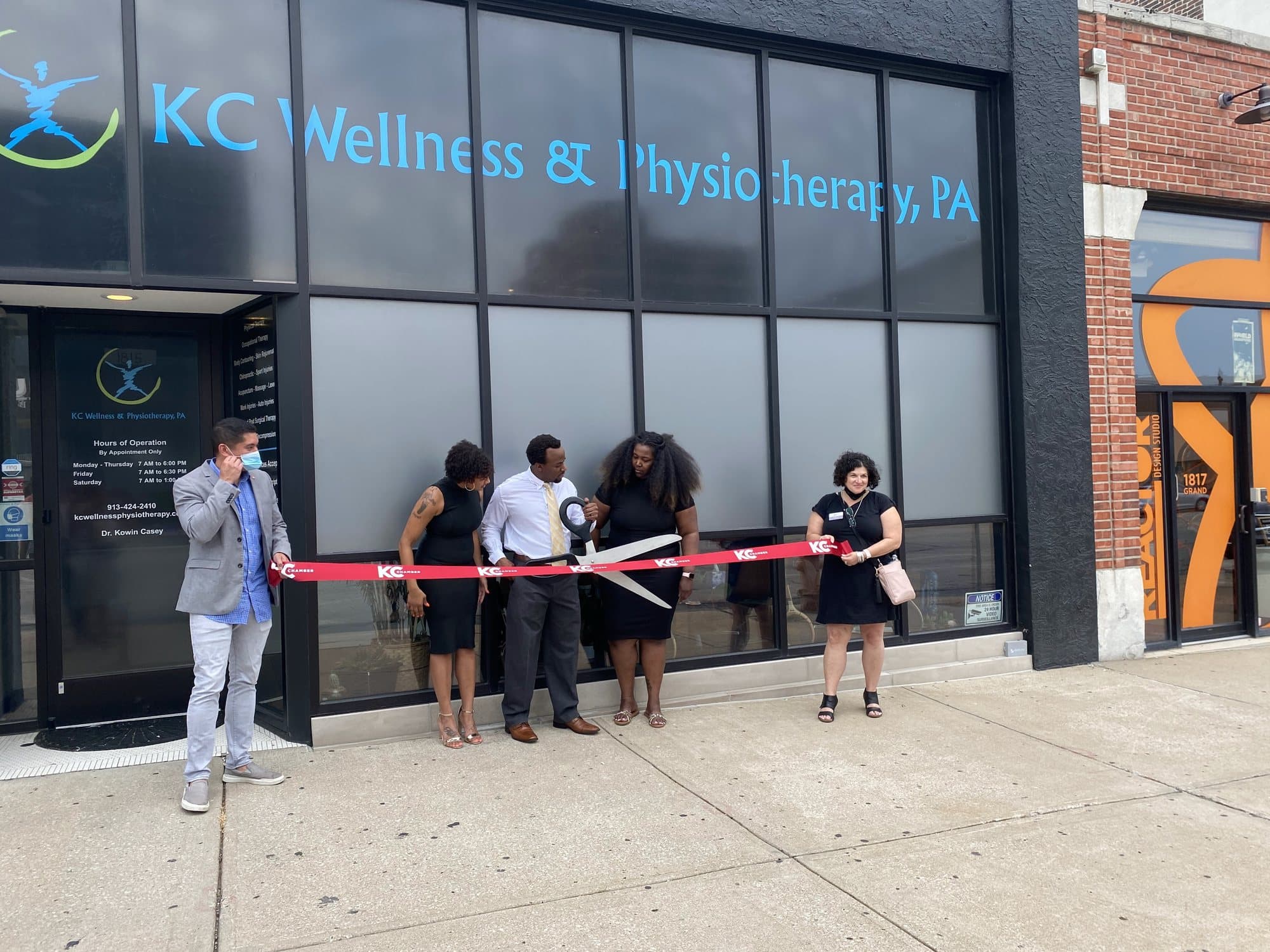 Ribbon cutting outside KC Wellness and Physiotherapy on Grand Blvd.