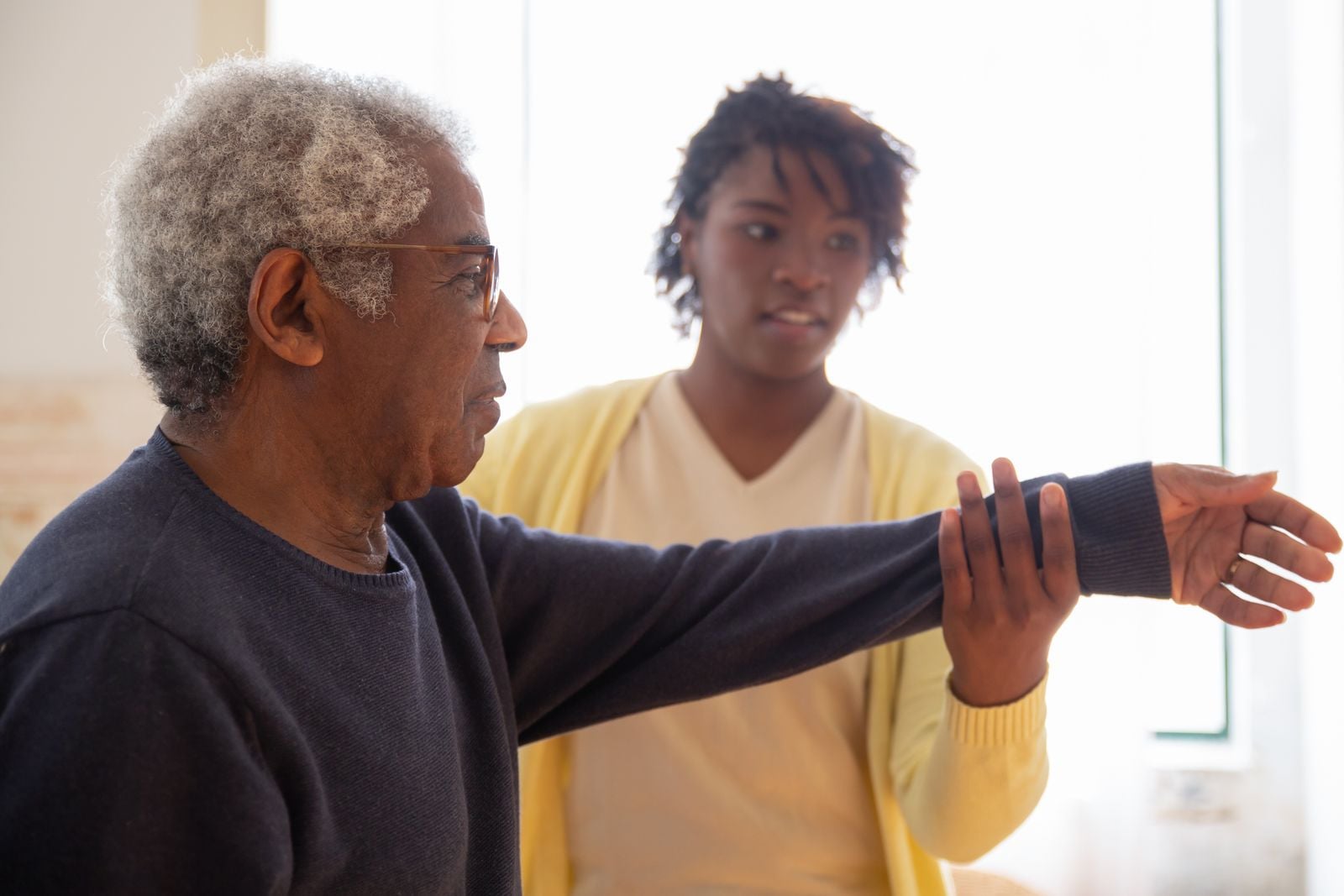 Woman guiding an older man through an assisted arm exercise