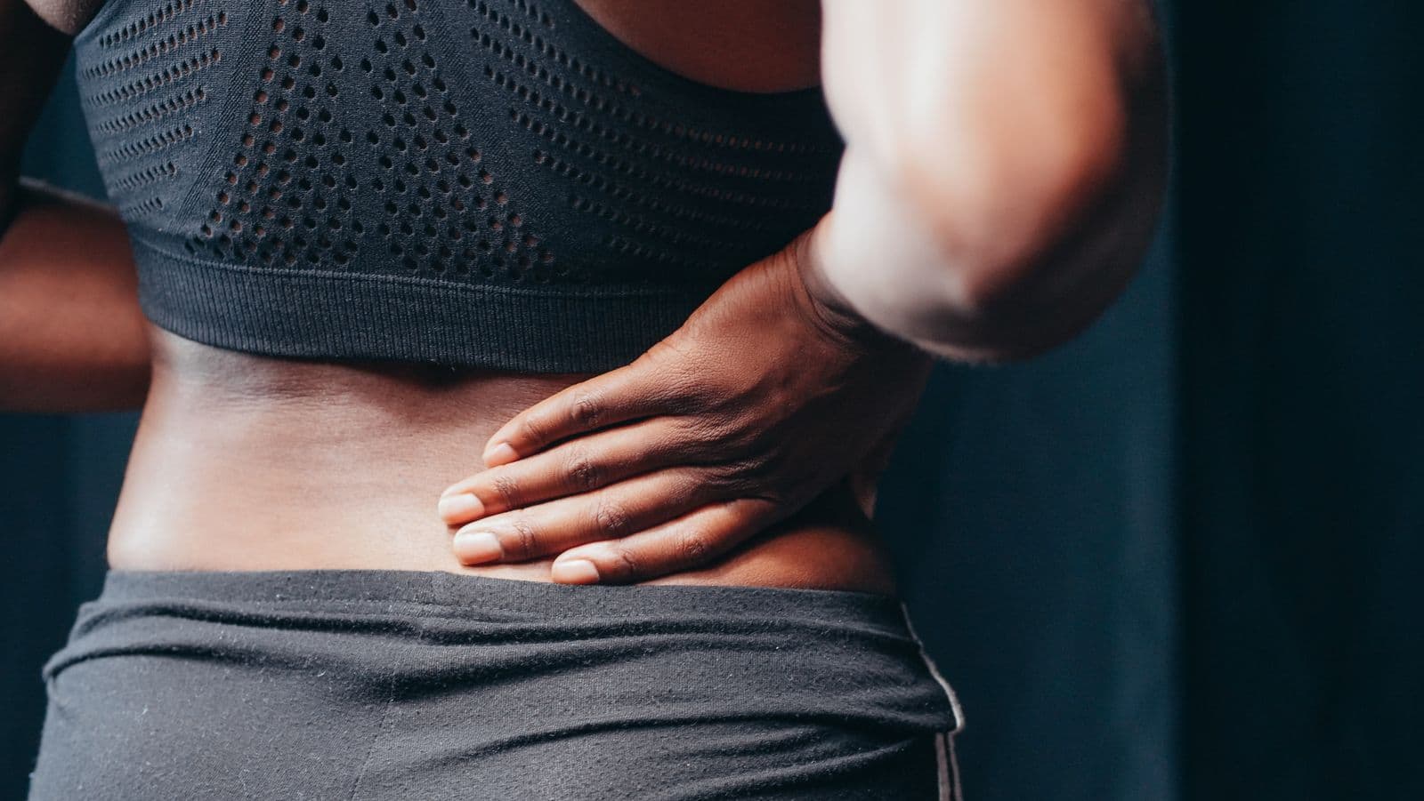 Woman pressing a hand to her sore lower back