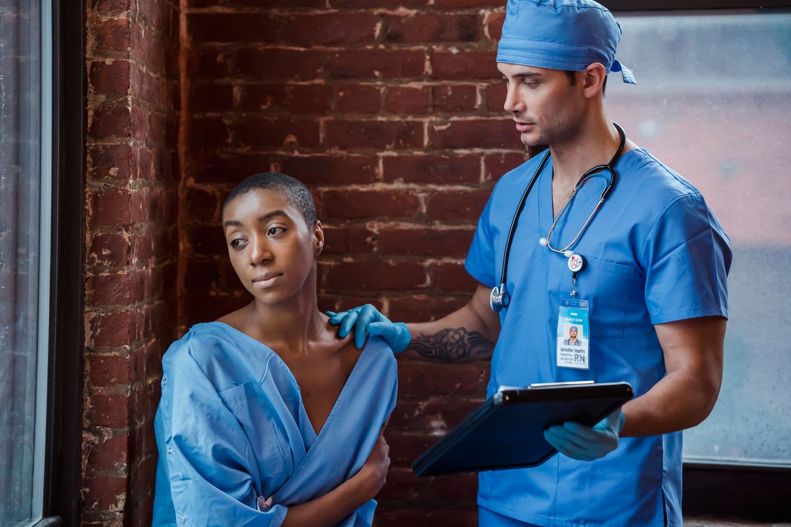 Clinician checking a seated woman's shoulder while reviewing notes on a clipboard