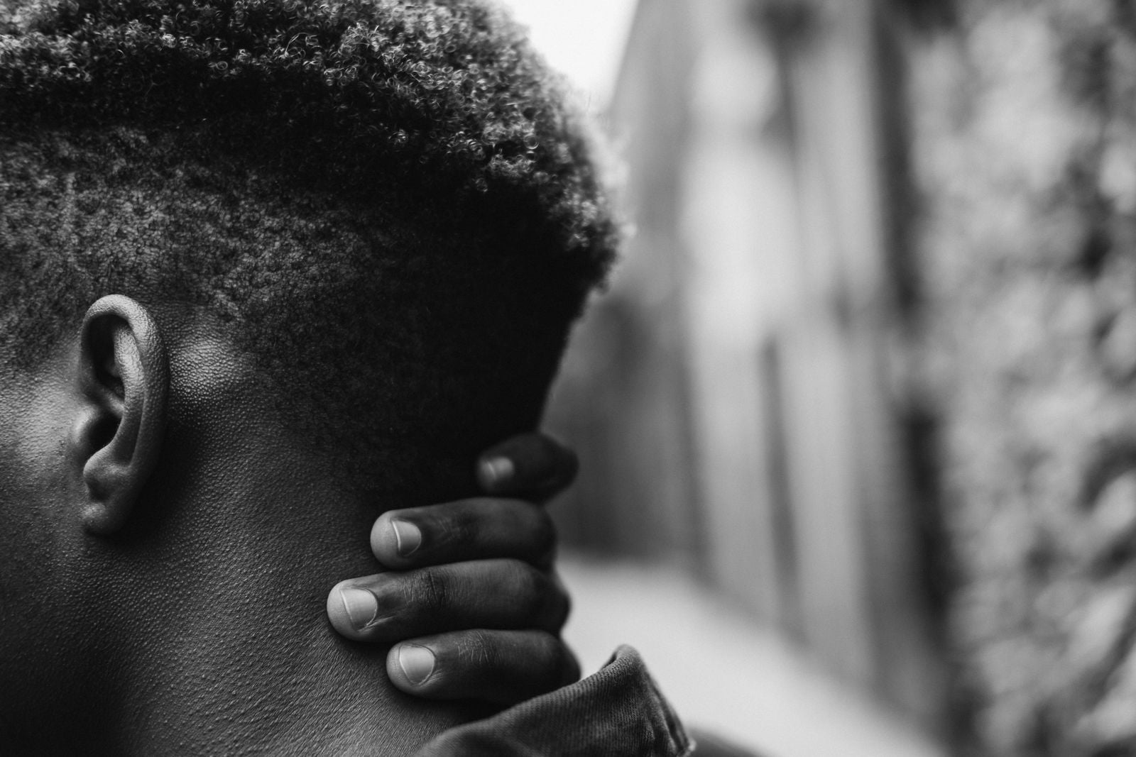 Black-and-white close-up of a man holding the back of his neck