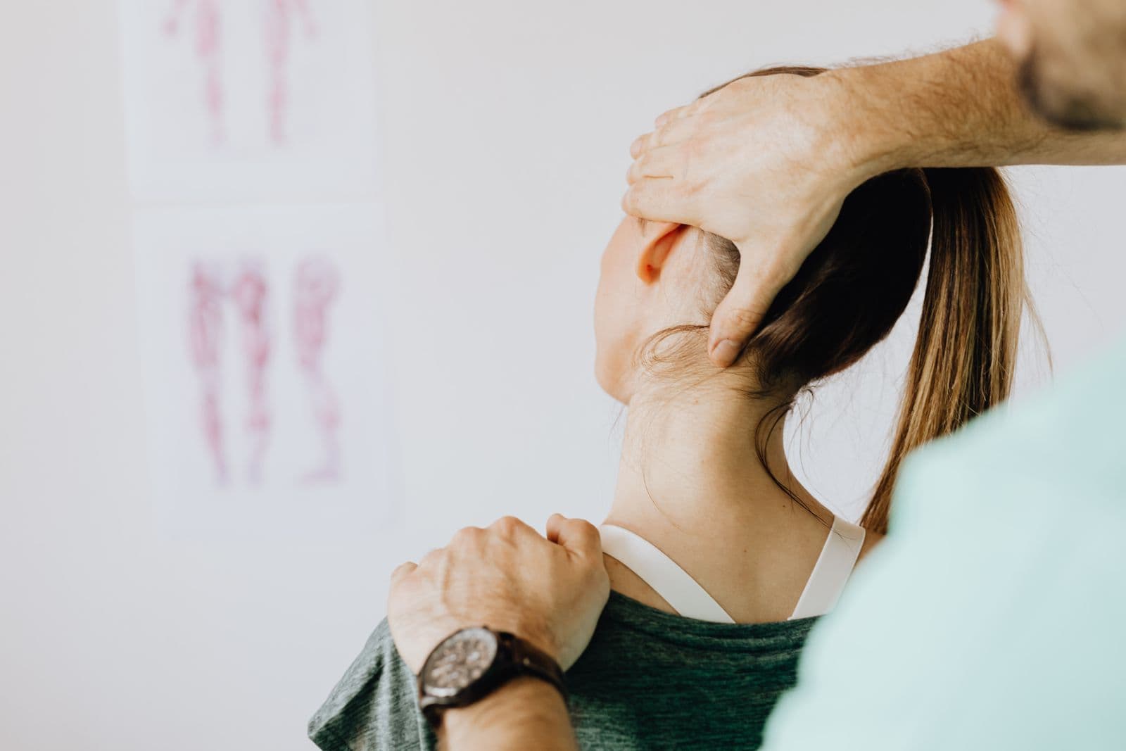 Clinician's hands supporting a patient's head and shoulder during a neck adjustment