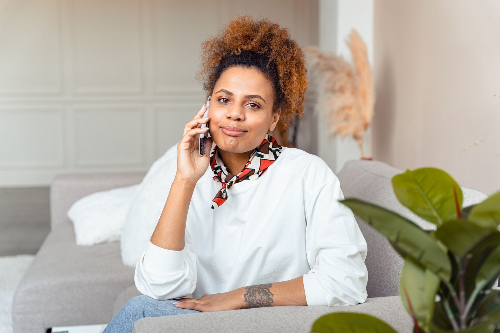 Woman smiling while talking on the phone on her couch at home