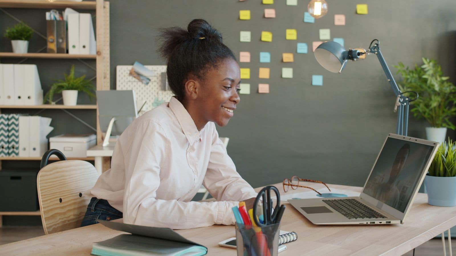 Young woman smiling during a video call on her laptop at a home desk