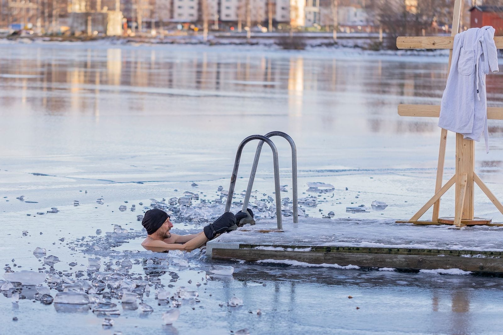 Illustrative stock photo of a man immersed in icy water beside a wooden dock