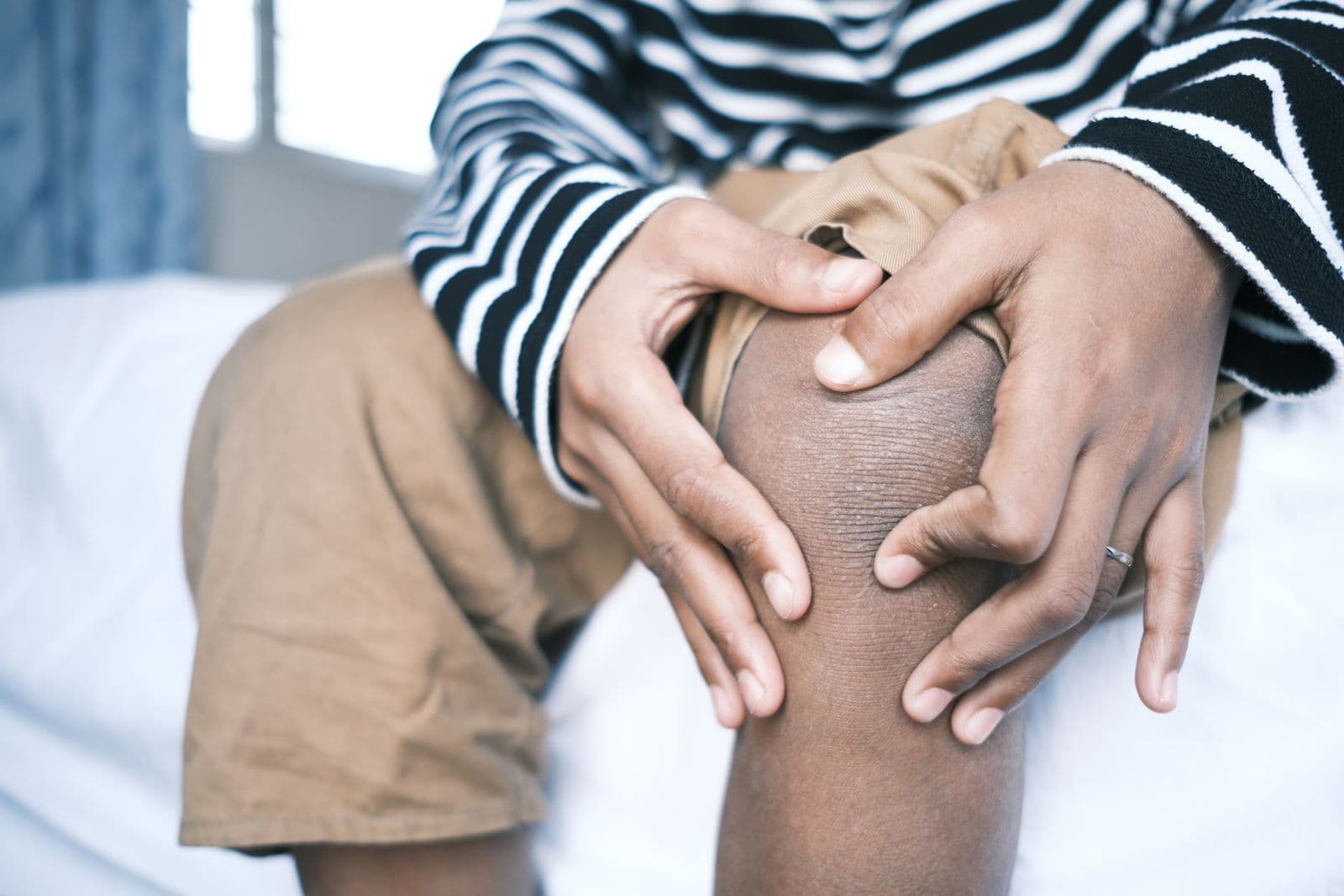 Person holding a sore knee with both hands