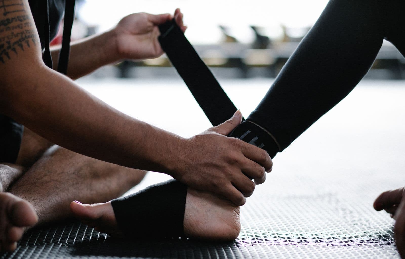 Athlete wrapping an injured ankle with an elastic bandage on a gym floor